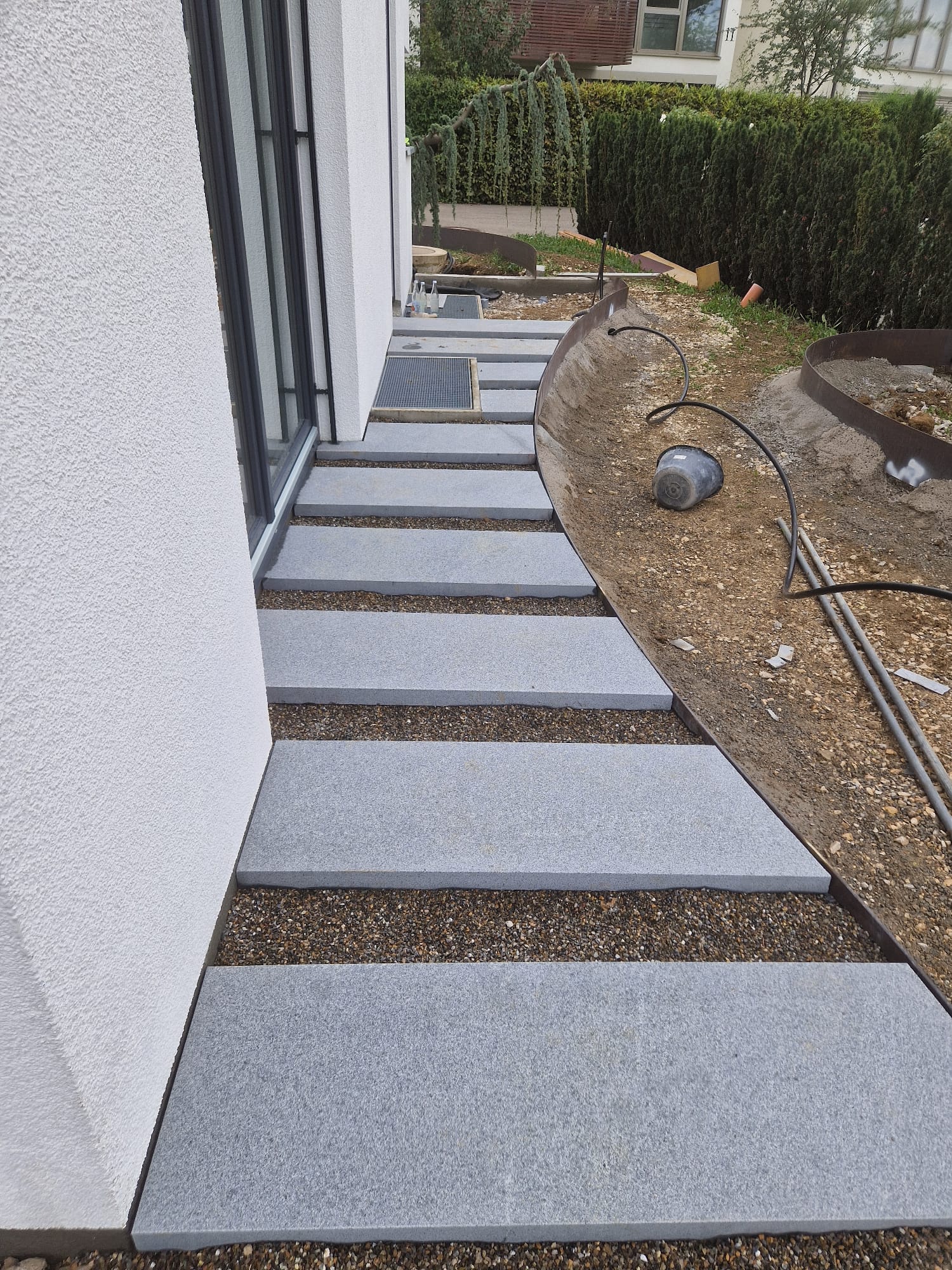 Trittplattenweg mit Naturstein-Einfassung am Haus